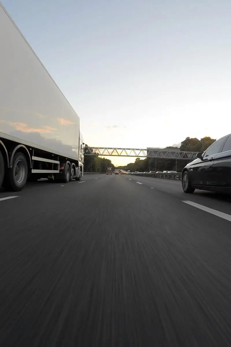Cars and a truck speed along a highway under the clear sky, showcasing transportation dynamics.